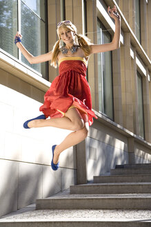 Vor Freude springende Frau im roten Kleid - MAEF00648