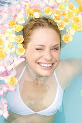 Germany, young woman in pool with flowers - BABF00348