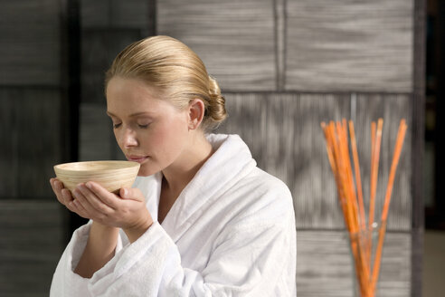 Germany, young woman holding tea bowl, close-up - BABF00311