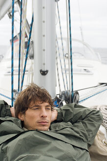 Germany, Baltic Sea, Lübecker Bucht, Young man lying on deck of yacht, portrait - BAB00429