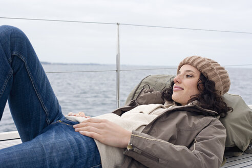 Germany, Baltic Sea, Lübecker Bucht, Young woman lying on deck of yacht, portrait - BAB00418