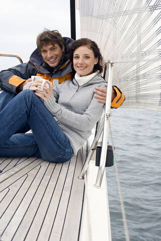 Germany, Baltic Sea, Lübecker Bucht, Young couple on sailing boat sitting and holding mugs stock photo