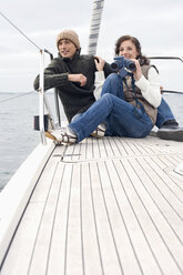Germany, Baltic Sea, Lübecker Bucht, Young couple on boat, woman holding binoculars - BAB00397