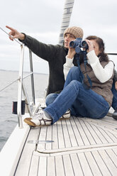 Deutschland, Ostsee, Lübecker Bucht, Junges Paar auf Boot, Frau schaut durch Fernglas - BAB00395