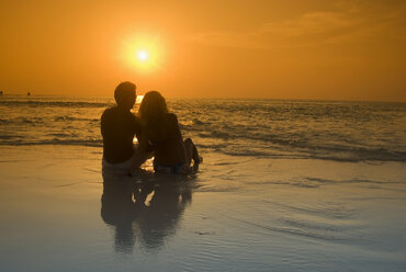 Paar am Strand sitzend, Silhouette bei Sonnenuntergang, Malediven - GNF00954