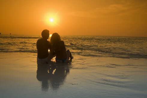 Paar am Strand sitzend, Silhouette bei Sonnenuntergang, Malediven - GNF00954