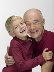 Grandson (8-9) embracing grandfather, smiling, portrait - WESTF06464