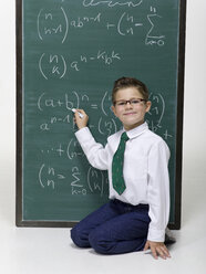 Boy (10-11) sitting in front of blackboard, portrait - WESTF06395