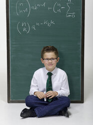 Boy (10-11) sitting in front of blackboard, portrait - WESTF06391