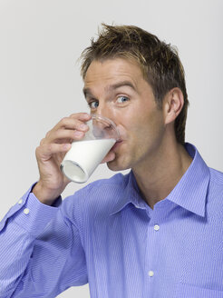 Young man drinking a glass of milk, portrait - WESTF06366