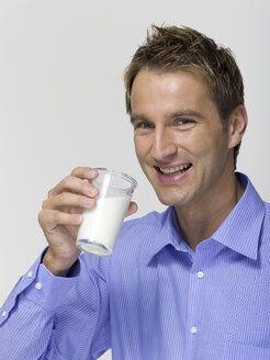 Young man drinking a glass of milk, portrait - WESTF06365