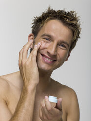 Young man applying face cream - WESTF06360