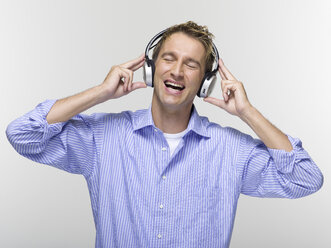 Young man with eyes closed listening to music - WESTF06356