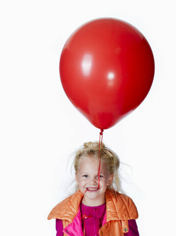 Mädchen (8-9) mit rotem Luftballon, Porträt, lizenzfreies Stockfoto