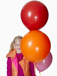 Mädchen (8-9) hält einen Strauß Luftballons, lächelnd, Porträt - KMF01133