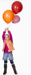 Girl (8-9) holding bunch of balloons, smiling, portrait - KMF01129