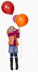 Girl (8-9) holding bunch of balloons, smiling, portrait - KMF01128