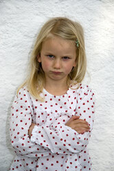 Mädchen (7-8) stehend mit verschränkten Armen, stirnrunzelnd, Porträt - NHF00671