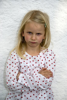 Girl (7-8) standing with arms crossed, frowning, portrait - NHF00671