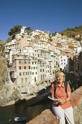 Italien, Ligurien, Riomaggiore, Frau sitzt auf Steinmauer - MRF01025