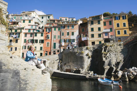 Italien, Ligurien, Riomaggiore, Frau sitzt auf Felsen, lizenzfreies Stockfoto