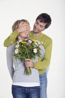Junger Mann gibt junger Frau einen Blumenstrauß, Porträt - WESTF06876
