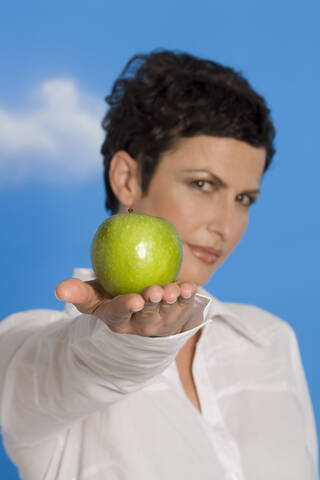 Junge Frau, die einen Apfel hält, Porträt, lizenzfreies Stockfoto