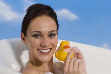 Junge Frau in der Badewanne mit Gummi-Ente, Porträt - RRF00020