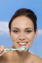 Young woman holding toothbrush, smiling, portrait - RRF00018