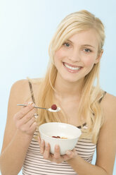 Young woman holding bowl of cereal, smiling - WESTF07006