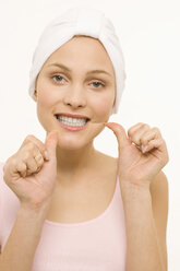 Nahaufnahme einer jungen Frau, die ihre Zähne mit Zahnseide reinigt - WESTF06980