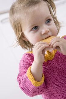 Baby girl (2-3) eating a biskuit, portrait - SMOF00136