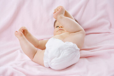 Baby-Mädchen (6-9 Monate) auf dem Bett liegend, Zehen berührend - SMOF00127