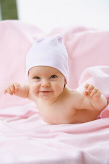 Baby Mädchen (6-9 Monate) auf dem Bauch liegend, lächelnd - SMOF00120