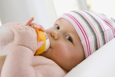 Kleiner Junge (6-9 Monate) trinkt Milch aus der Flasche, Porträt - SMOF00100