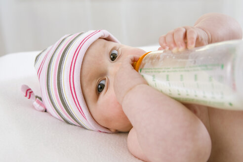 Kleiner Junge (6-9 Monate) trinkt Milch aus der Flasche, Porträt - SMOF00098