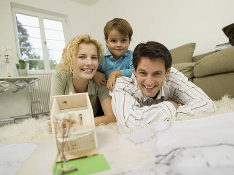 Junge Familie im Wohnzimmer, lächelnd, Porträt, lizenzfreies Stockfoto