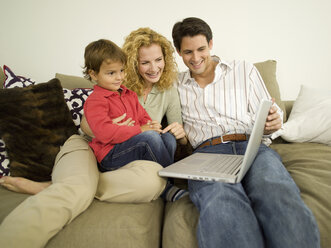 Young family in living room, father using laptop - WESTF06651