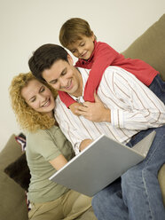 Young family in living room, father using laptop - WESTF06649