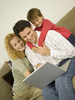 Junge Familie im Wohnzimmer, Vater am Laptop - WESTF06649