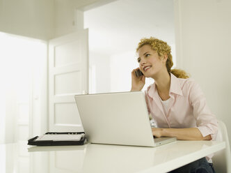 Young woman using mobile phone, smiling - WESTF06616