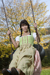 Brunette woman in dirndl dress, swinging, portrait - MAEF00792