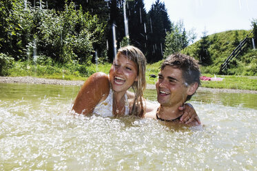 Young couple splashing in water, portrait - HHF01644