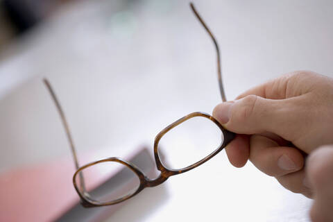 Menschliche Hand, die eine Brille hält, lizenzfreies Stockfoto