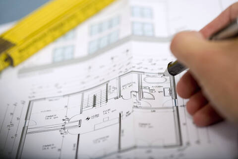 Man's hand pointing at blueprint with pen stock photo