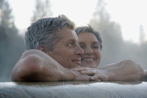 Mature couple relaxing in outdoor spa, portrait - WESTF07743