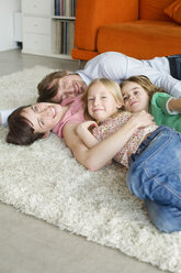 Family lying on floor in living room - WESTF07401