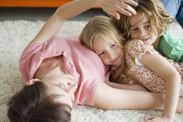 Mother and children lying on floor in living room, portrait - WESTF07400