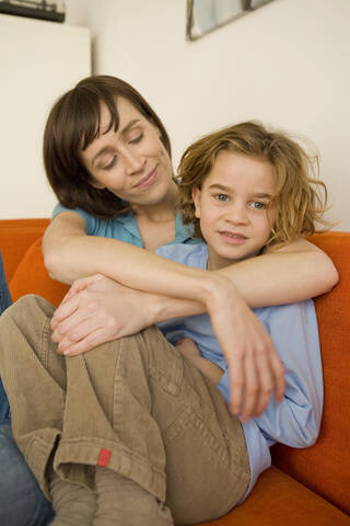 Mutter und Sohn (6-7) auf dem Sofa sitzend, Porträt, lizenzfreies Stockfoto