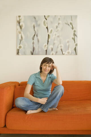 Junge Frau auf dem Sofa sitzend, Porträt, lizenzfreies Stockfoto